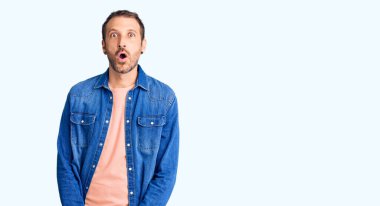 Gündelik kıyafetler giyen genç, yakışıklı bir adam. Şaşırmış ve korkmuş bir ifade, korku ve heyecanlı bir yüz ifadesi.. 