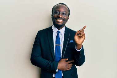 Yakışıklı, genç, siyah takım elbiseli, kravatlı, gülümseyen, mutlu, eli ve parmağı yanda olan bir adam. 