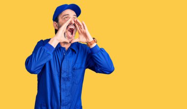 Orta yaşlı, yakışıklı, tamirci üniforması giyen ve elleri ağzında kızgın bir şekilde bağıran bir adam. 