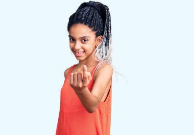 Şirin Afro-Amerikan kızı, günlük giysiler giymiş, el kol hareketi yaparak, mutlu bir şekilde karşılamaya ve gülümsemeye davet ediyor. 