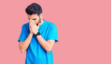 Sakallı, sıradan tişörtlü, suratını ellerle kapatıp ağlayan genç yakışıklı bir adam. depresyon kavramı. 