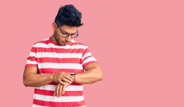 Yakışıklı Latin Amerikalı, günlük kıyafetler ve gözlük takmış. Saati kontrol ediyor. Rahat ve kendinden emin. 