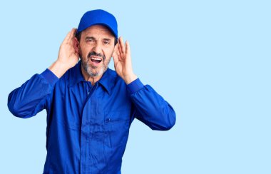 Orta yaşlı, tamirci üniforması giyen yakışıklı bir adam iki elini de kulak hareketine sokmaya çalışıyor. Dedikoduya meraklı. İşitme sorunu, sağır 