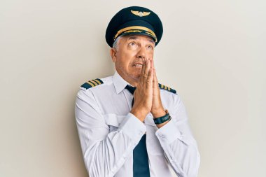 Yakışıklı, olgun bir adam, uçak pilotu üniforması giyiyor. Elleriyle yalvarıyor ve dua ediyor. Yüzünde umut ifadesi var. Yalvarıyor. 