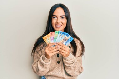 Genç, İspanyol asıllı, elinde İsviçre frangı banknotlarıyla gülümseyen güzel bir kız. diş gösterme. 