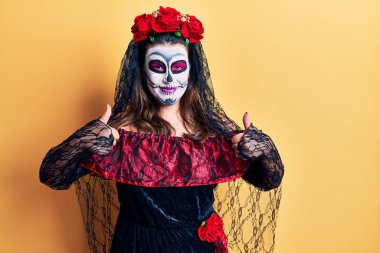 Sarı işaret üzerine ölü kostümü giymiş genç bir kadın elleriyle olumlu jest yapıyor, gülümsüyor ve mutlu. Neşeli ifade ve kazanan jest. 