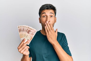 Güney Kore 'yi elinde tutan genç yakışıklı adam, ağzı kapalı, şok olmuş ve hata yapmaktan korkan banknotlar kazandı. şaşırmış ifade 