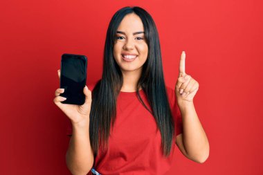 Genç, İspanyol asıllı güzel bir kız elinde akıllı telefonla ekranda gülümseyen bir fikir ya da soruyla mutlu bir yüzle işaret ediyor. 