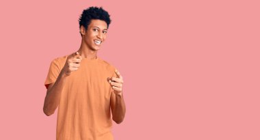 Sıradan kıyafetler giymiş genç Afro-Amerikalı adam mutlu ve komik yüzüyle kamerayı işaret ediyor. iyi enerji ve titreşimler. 