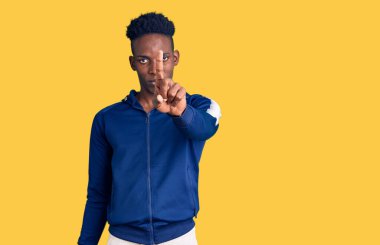 Afro-Amerikalı genç adam spor giyer, parmağını kaldırır ve kızgın bir ifade takınır. 