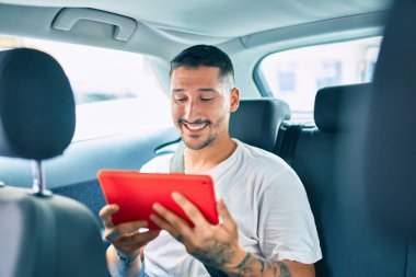 Genç İspanyol adam mutlu bir şekilde gülümsüyor. Arabada dokunmatik ped kullanıyor..