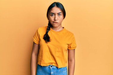 Gündelik kıyafetler giyen genç Latin kadın şüpheci ve gergin, sorun yüzünden surat asıyor. negatif kişi. 