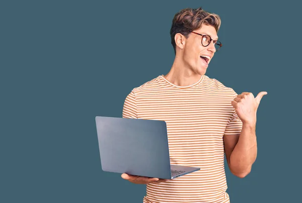 Młody Przystojny Mężczyzna Okularach Trzymający Laptop Skierowany Kciuk Górę Boku — Zdjęcie stockowe