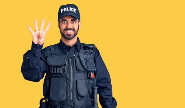 Young hispanic man wearing police uniform showing and pointing up with fingers number four while smiling confident and happy.