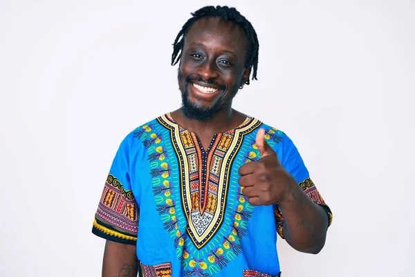 伝統的なアフリカのTシャツを着た若いアフリカ系アメリカ人の男は 幸せと肯定的な笑みを浮かべて 親指アップ素晴らしいと承認サインを行う — ストック写真