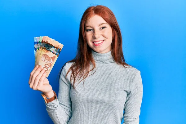 Joven Chica Pelirroja Sosteniendo Dólares Canadienses Mirando Positiva Feliz Pie — Foto de Stock