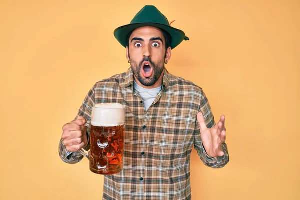 Schöner Hispanischer Mann Mit Bart Oktoberfestmütze Bier Trinkend Erschrocken Und — Stockfoto