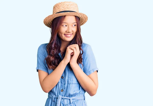 年轻美丽的中国姑娘戴着夏帽 紧张地笑着 双手托着下巴朝外看 兴奋极了 — 图库照片