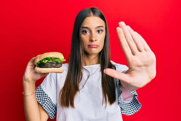 Fiatal Spanyol Eszik Hamburger Nyitott Kézzel Csinál Stop Tábla Komoly — Stock Fotó