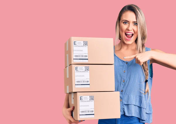 Young Beautiful Blonde Woman Holding Delivery Boxes Smiling Happy Pointing — Stock Photo, Image