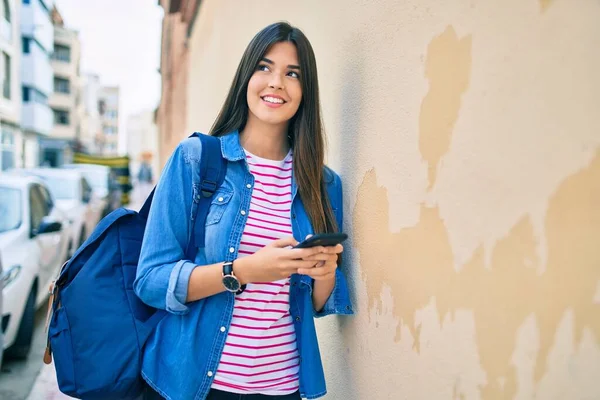 若いですヒスパニック系の学生の女の子笑顔幸せな使用スマートフォンで市内 — ストック写真