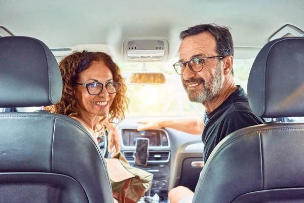 Middle age beautiful couple on vacation wearing glasses smiling happy driving car.