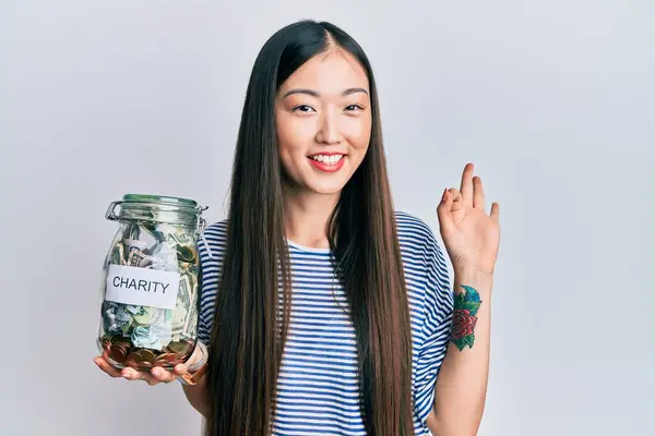 Mladá Číňanka Drží Charitativní Sklenici Penězi Dělá Znamení Prsty Usmívá — Stock fotografie
