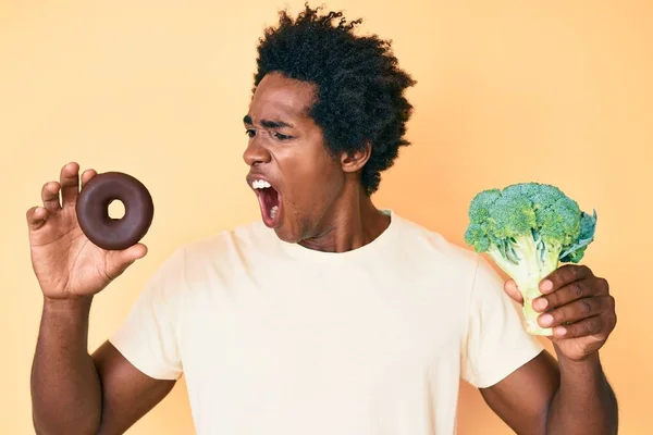 Hombre Afroamericano Guapo Con Pelo Afro Sosteniendo Brócoli Donut Chocolate —  Fotos de Stock