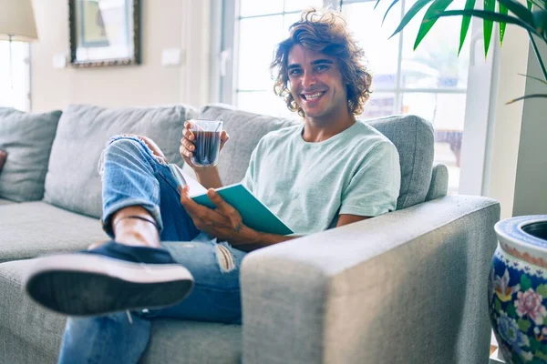 Joven Hispano Sonriendo Feliz Leyendo Libro Tomando Café Casa —  Fotos de Stock