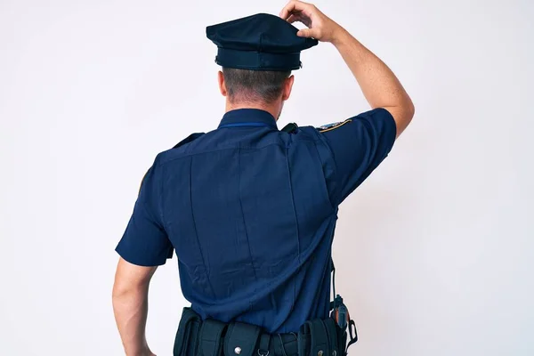 若いです白人男性を着て警察制服後方頭の上に手で疑問について考えて — ストック写真