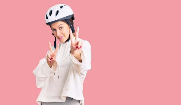 자전거 헬멧을 운동복을 아름다운 갈색의 여성이 카메라 앞에서 손가락이 승리의 — 스톡 사진