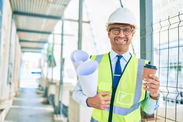 コーヒーを飲む反射ベストを身に着けている建物のプロジェクトの屋外に立つハードハットを身に着けているビジネスアーキテクトの男 — ストック写真