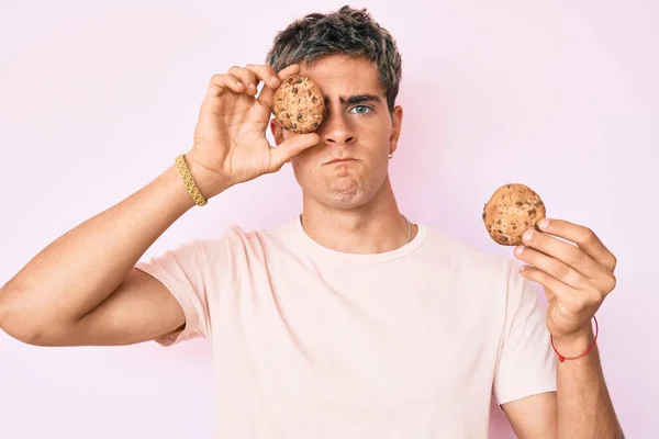 Jeune Homme Beau Tenant Cookie Sceptique Nerveux Fronçant Les Sourcils — Photo