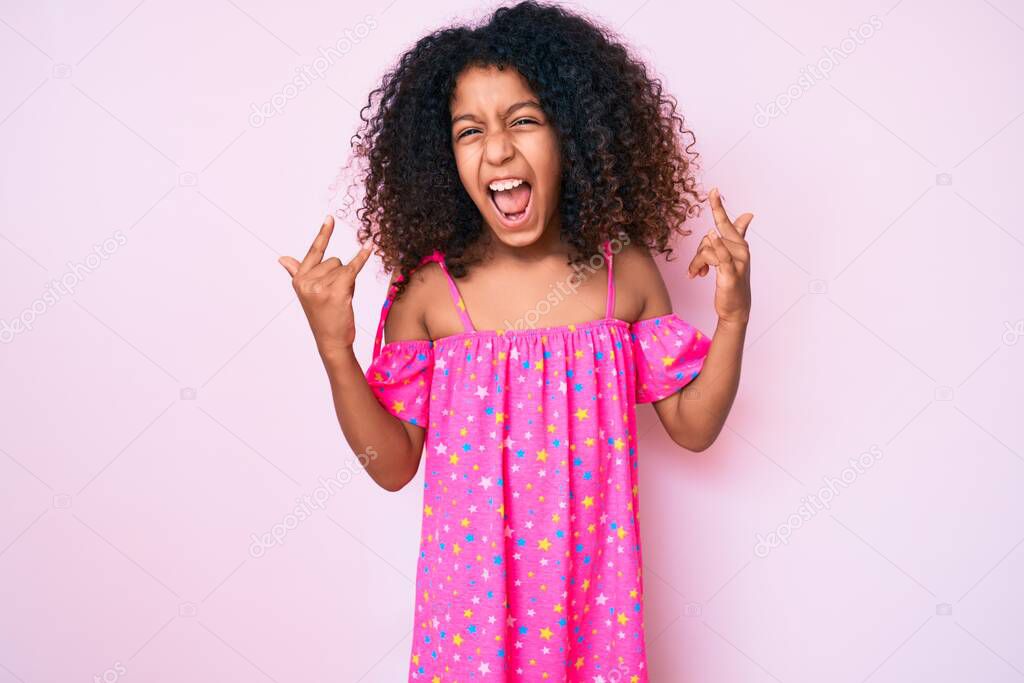 African american child with curly hair wearing casual dress shouting with crazy expression doing rock symbol with hands up. music star. heavy concept. 