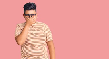 Günlük kıyafetler giyen ve gözlük takan küçük çocuk pis ve iğrenç bir koku alıyor. Nefesini burnunda tutuyor. Kötü kokuyor. 