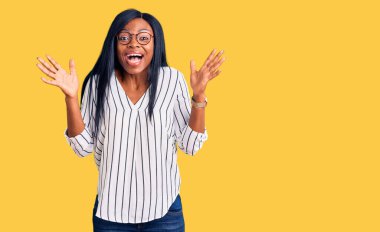 Genç Afro-Amerikalı kadın gündelik kıyafetler ve gözlük takarak çılgın kutlamalar yapıyor ve başarıyı kollarını kaldırıp heyecanla haykırarak kutluyor. Kazanan konsept 