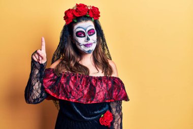 Sarı üzerine ölü kostümü giymiş genç bir kadın bir numaralı parmağını gösterip gülümserken kendinden emin ve mutlu.. 