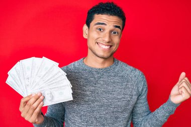 Elinde dolar sembolü olan genç, yakışıklı İspanyol adam gururla bağırıyor, zaferi kutluyor ve kollarını kaldırarak çok heyecanlanıyor. 