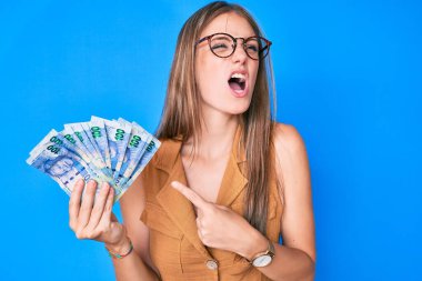 Güney Afrika rand 'ini elinde tutan genç sarışın kız kızgın ve öfkeli çığlıklar atıyor öfkeyle bağırıyor. öfke ve agresif konsept. 