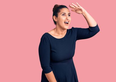 Genç, güzel, esmer, gündelik elbiseler giyen çok mutlu ve gülümseyerek başını kaldırmış uzaklara bakan bir kadın. arama kavramı. 