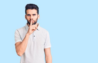 Sakallı, sıradan polo giyen genç ve yakışıklı bir adam parmakları dudaklarında sessiz olmak istiyor. sessizlik ve gizli konsept. 