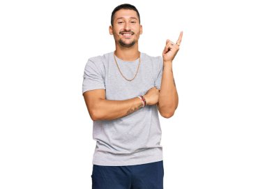 90 'ların stili dövmeli yakışıklı bir adam. Yüzünde kocaman bir gülümseme var. Elleri ve parmaklarıyla kameraya bakıyor.. 