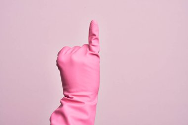 İzole edilmiş pembe arka planda temiz eldiveni olan beyaz bir gencin eli serçe parmağının söz verme sözü olduğunu gösteriyor.
