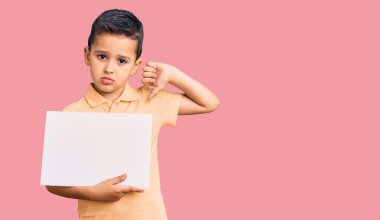 Elinde boş yeri olan, kızgın yüzüyle karton pankart tutan küçük şirin bir çocuk. Negatif işaret baş parmakları aşağıda, reddedilme konsepti. 