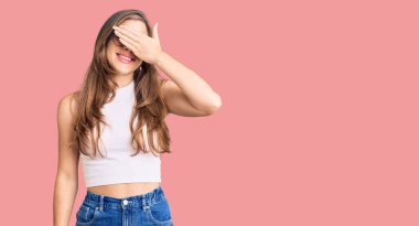 Gündelik giysiler ve gözlük takan güzel beyaz bir kadın. Gülümsüyor ve yüzünde şaşkınlık için gözleri kapatan bir el ile gülüyor. kör kavram. 