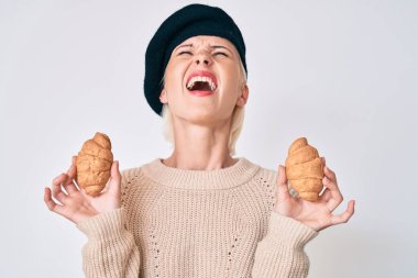Fransız tarzı giyinen genç beyaz bir kadın elinde kruvasanlarla kızgın ve öfkeli bir şekilde bağırıyor öfkeyle yukarı bakıyor.. 