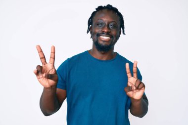 Saçları örgülü, gülümseyerek kameraya bakıp zafer işareti yapan Afro-Amerikalı genç bir adam. İki numara.. 