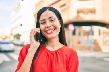 Genç Latin kız gülümsüyor. Şehirdeki akıllı telefondan konuşuyor..