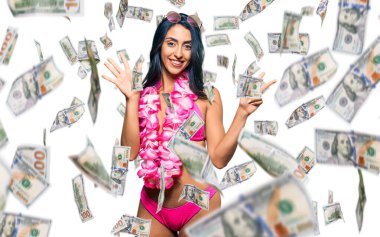 Güzel İspanyol kadın bikini giyiyor ve Hawaii zambağı sekiz numarayı gösterip işaret ederken kendinden emin ve mutlu gülümsüyor..