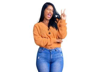 Uzun saçlı, sıradan bir kazak giyen, kameraya gülümseyen ve zafer işareti yapan İspanyol bir kadın. İki numara.. 